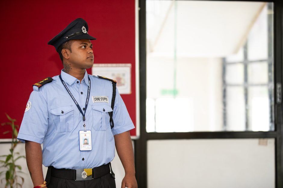 Photo by Anil Sharma on Pexels Uniformed security guard standing on duty beside a glass entrance. Photo by Anil Sharma on Pexels