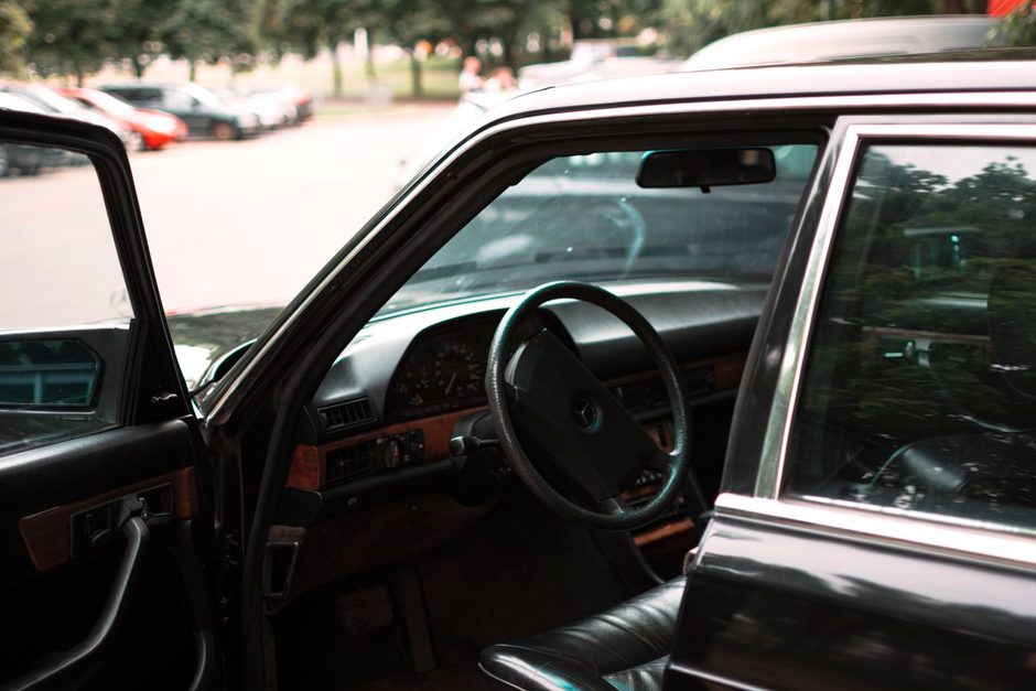 Open car door showing a vintage car interior and steering wheel. Photo by Vitali Adutskevich on Pexels