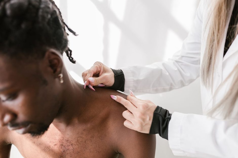 Dermatologist examining a patient's neck and skin during a clinic consultation. Photo by RDNE Stock project on Pexels