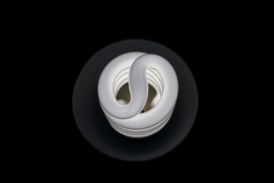 Minimalist top view of a CFL light bulb on a black background, showcasing modern design. Photo by Arturo A on Pexels