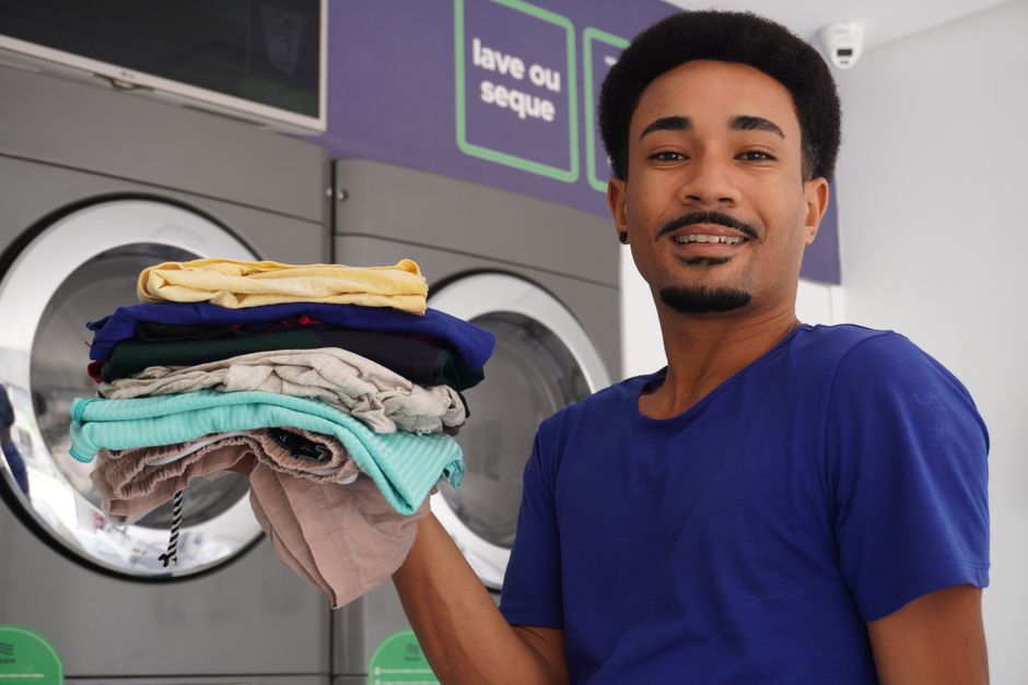 A happy man holding freshly washed clothes at a laundromat in Pernambuco, Brazil. Photo by Gyldo . on Pexels