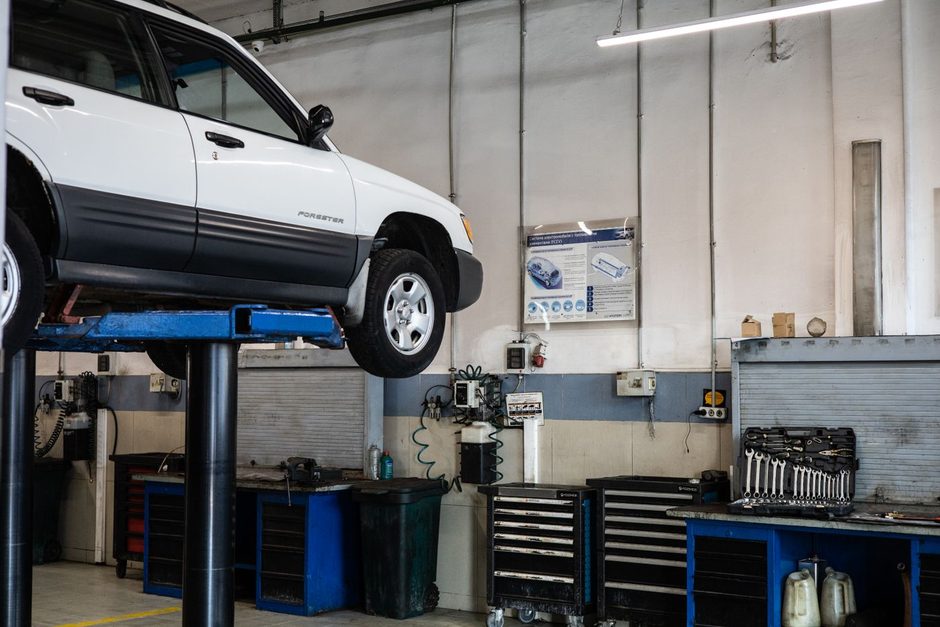 Car raised on a lift inside a bright oil change service bay. Photo by Artem Podrez on Pexels