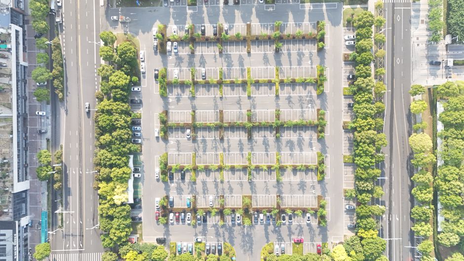 Aerial view showcasing an organized city parking lot lined with trees and parked cars. Photo by umar muazu on Pexels