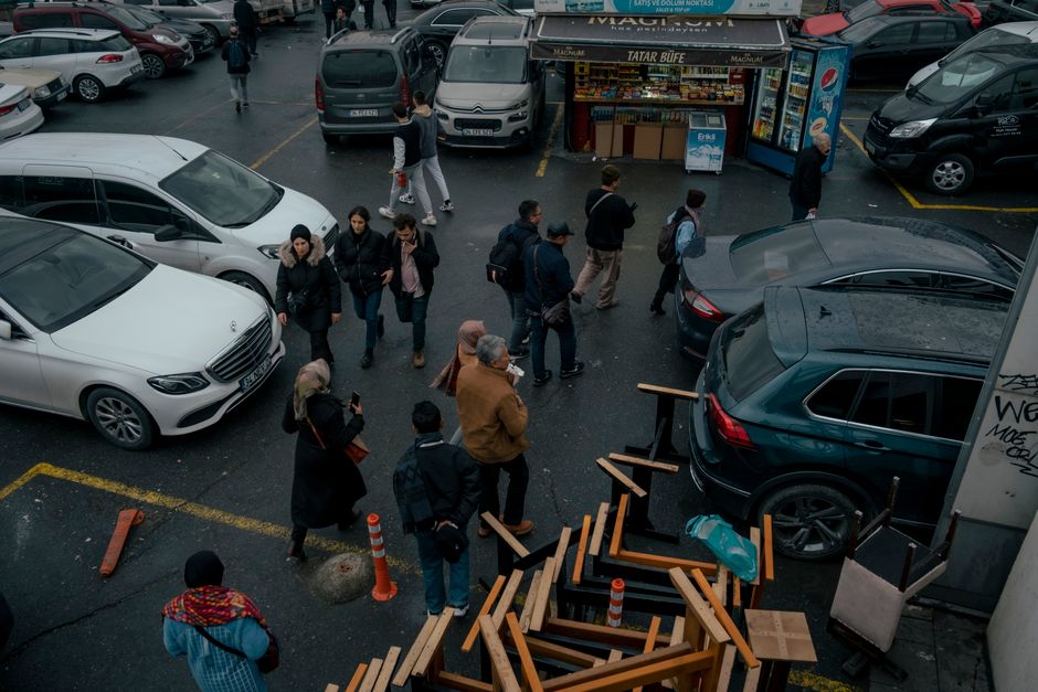 A bustling urban parking lot with people walking and various parked cars, capturing daily life activity. Photo by Zeynep Sude  Emek on Pexels