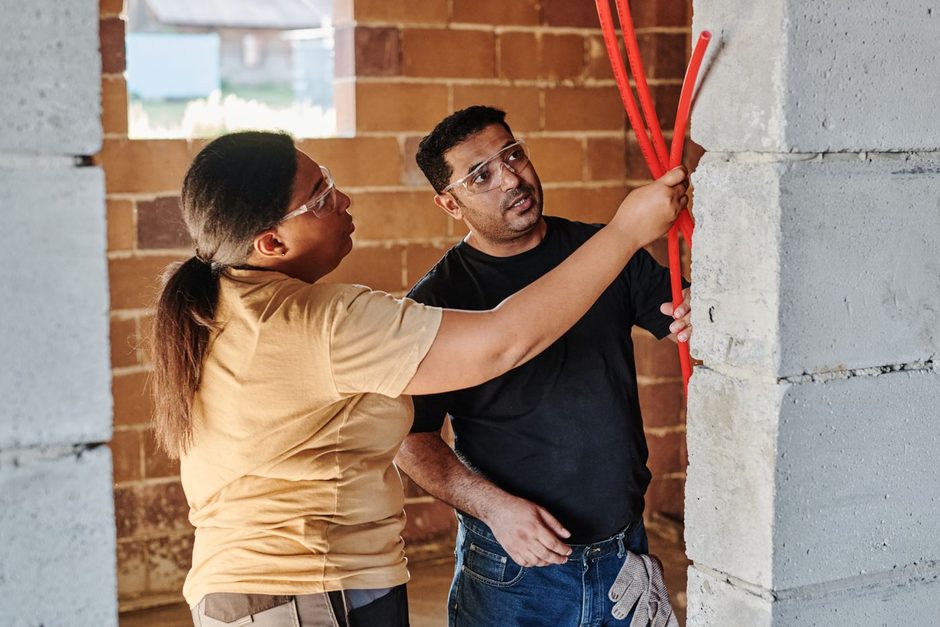 Photo by Mikael Blomkvist on Pexels Electrician and homeowner pulling red cable through a brick wall during an installation. Photo by Mikael Blomkvist on Pexels