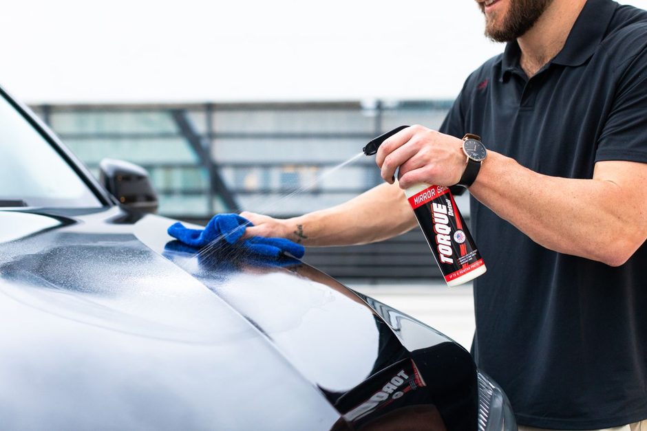Photo by Torque Detail on Pexels Detailer in a black polo applying product to a car with a blue cloth. Photo by Torque Detail on Pexels