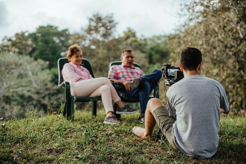 Photographer hands holding a camera beside an open laptop for editing. Photo by Luis Quintero on Pexels