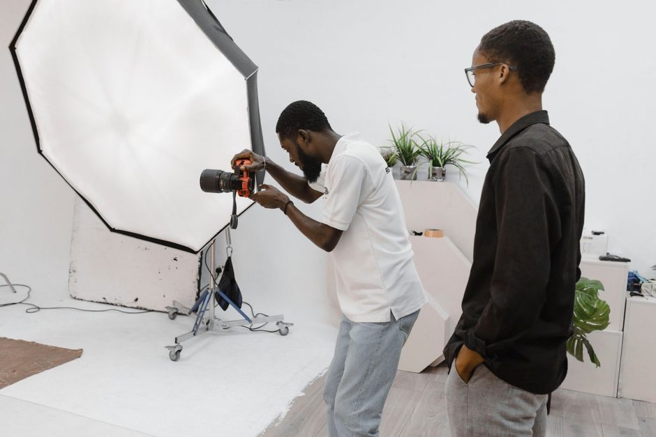 Photographer showing a client results in a bright white photo studio. Photo by Alfredo Dacosta on Pexels
