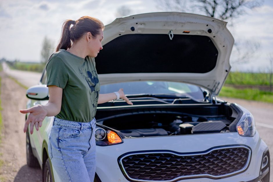 Woman beside a broken down car with its hood open on a road. Photo by Atlantic Ambience on Pexels