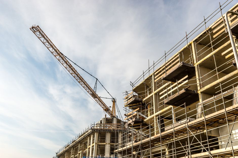 A dynamic view of a construction site with crane and scaffolding on a sunny day. Photo by Mike van Schoonderwalt on Pexels