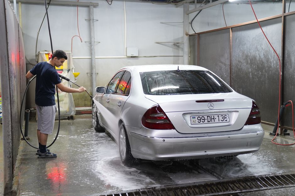Photo by Tahir Xəlfəquliyev on Pexels A young man using a hose to wash a silver car inside an indoor car wash facility. Photo by Tahir Xəlfəquliyev on Pexels