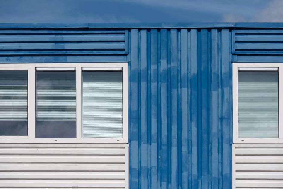 Photo by Jan van der Wolf on Pexels Close-up of a blue industrial building facade with two windows and metal siding under clear sky. Photo by Jan van der Wolf on Pexels