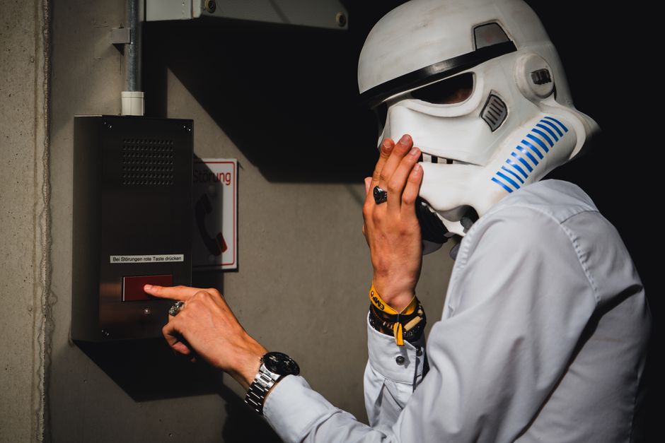 Photo by Oliver Schröder on Pexels A person wearing a Stormtrooper helmet interacts with an intercom in an indoor setting. Photo by Oliver Schröder on Pexels