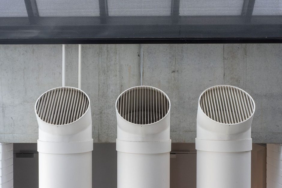 Row of white ventilation ducts mounted along a concrete ceiling. Photo by Jan van der Wolf on Pexels