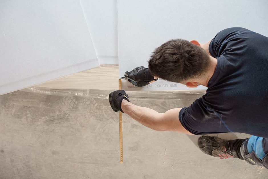Installer in gloves measuring a floor surface with a tape measure. Photo by Jimmy Nilsson Masth on Pexels