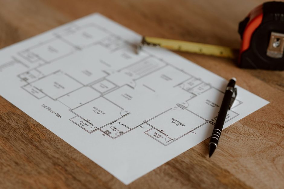 Floor plan on a desk with a tape measure and pencil. Photo by Anete Lusina on Pexels