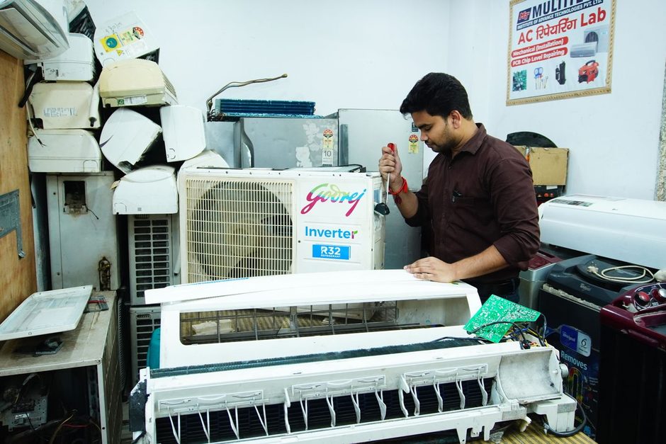 Technician servicing a white air conditioning unit. Photo by Multitech Institute on Pexels