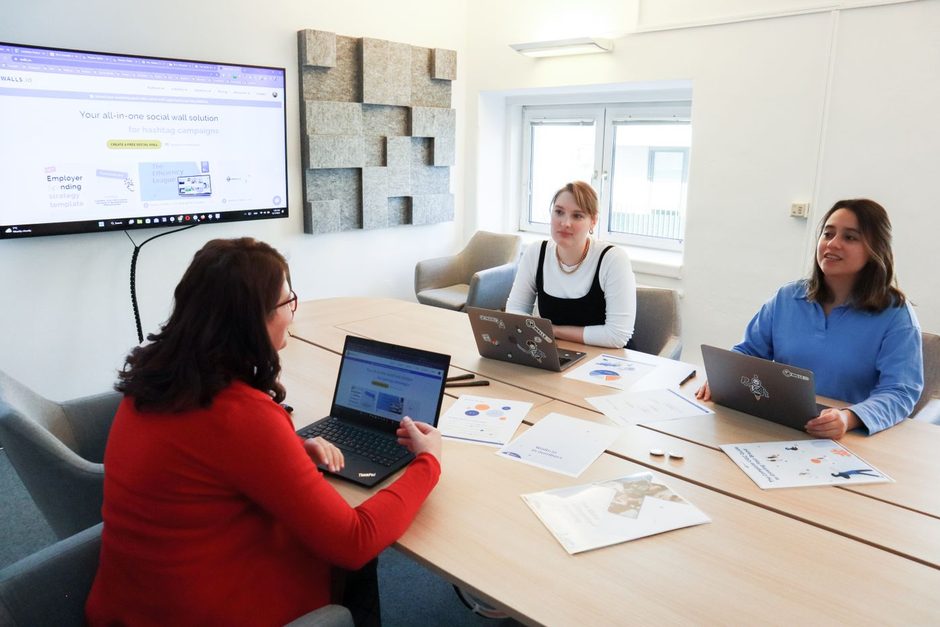 Marketing team gathered around a table with laptops in a bright office. Photo by Walls.io on Pexels