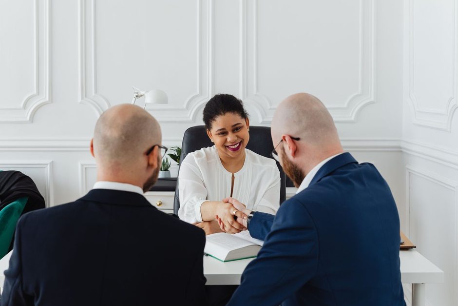 Financial advisor and clients reviewing documents together at a desk in a bright office. Photo by https://kaboompics.com/ on Pexels
