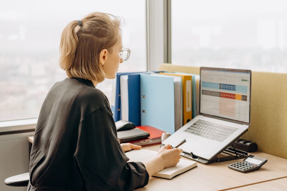 Sales manager at a desk with a laptop showing a CRM dashboard and folders. Photo by Mikhail Nilov on Pexels