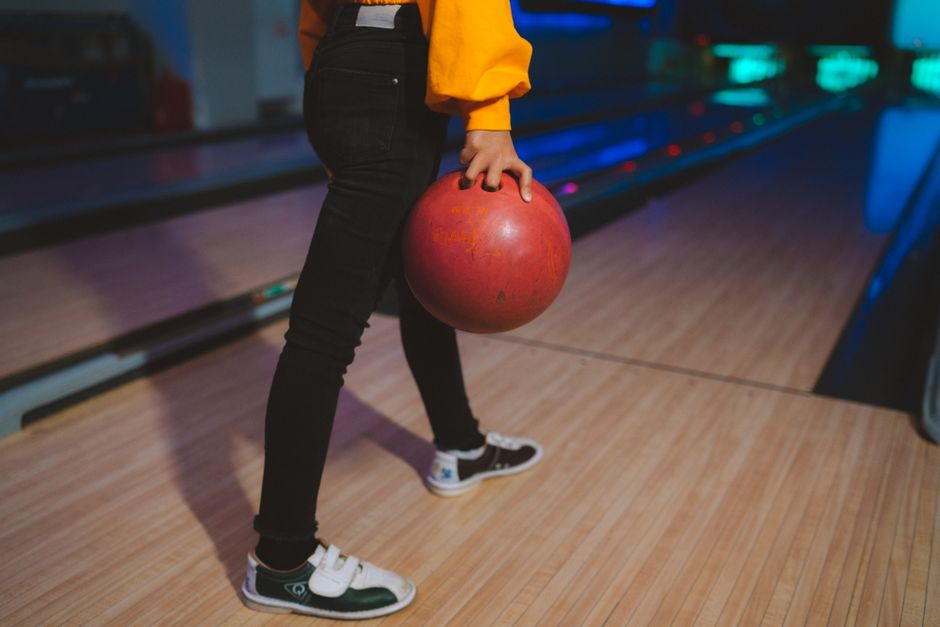 Close-up of a person holding a bowling ball at a bowling alley with vibrant lighting. Photo by Anastasia  Shuraeva on Pexels