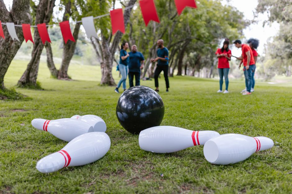 A group of adults playing inflatable bowling for team building outdoors. Photo by RDNE Stock project on Pexels