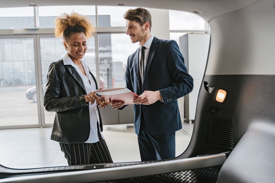 Dealer discussing vehicle options with a client inside a modern car showroom. Photo by Antoni Shkraba on Pexels