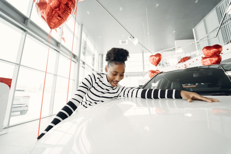 Photo by Gustavo Fring on Pexels Excited woman embraces her new car at a dealership, surrounded by red balloons. Photo by Gustavo Fring on Pexels
