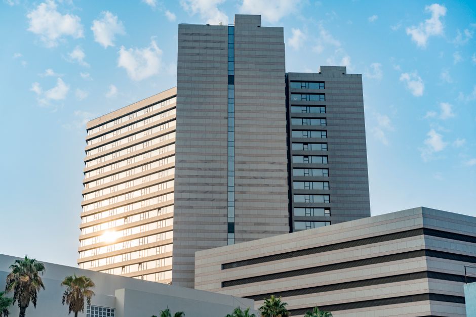 A sleek, modern skyscraper featuring a reflective glass facade under a clear blue sky. Photo by Marik Elikishvili on Pexels