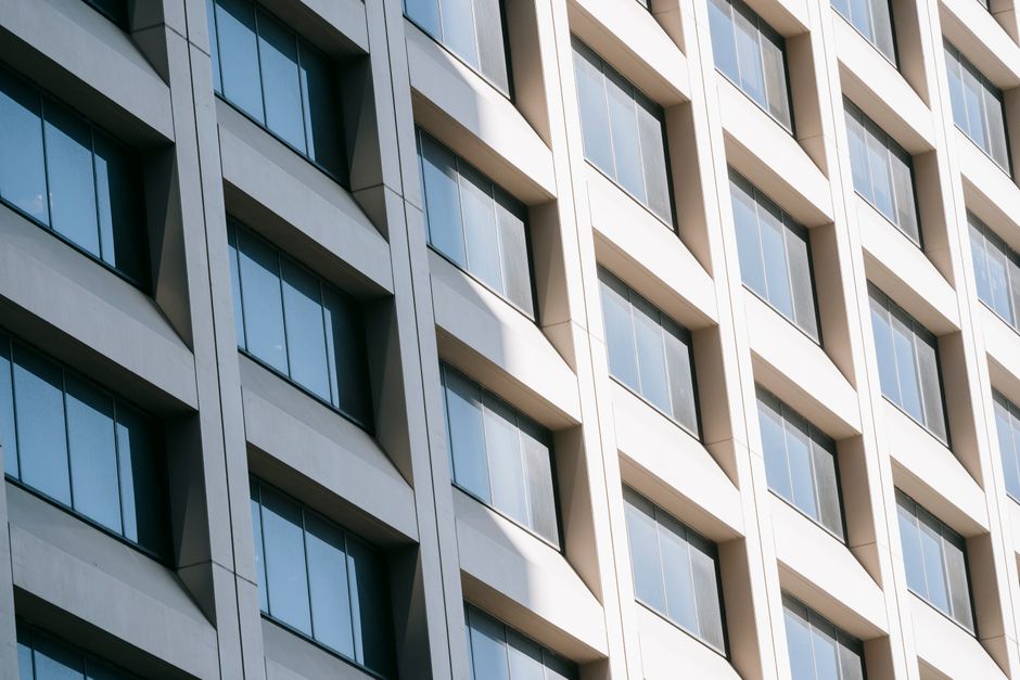 Low angle of rows of modern glass windows on facade of contemporary white multistory building reflecting sunlight. Photo by Laura Tancredi on Pexels