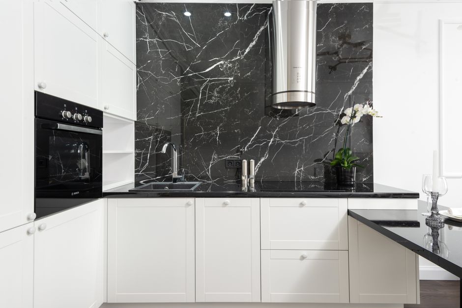 Sleek contemporary kitchen featuring white cabinets and black marble backsplash for a clean, minimalistic design. Photo by Max Vakhtbovych on Pexels