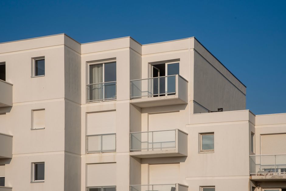A view of a contemporary white apartment complex under a clear blue sky. Photo by Jan van der Wolf on Pexels