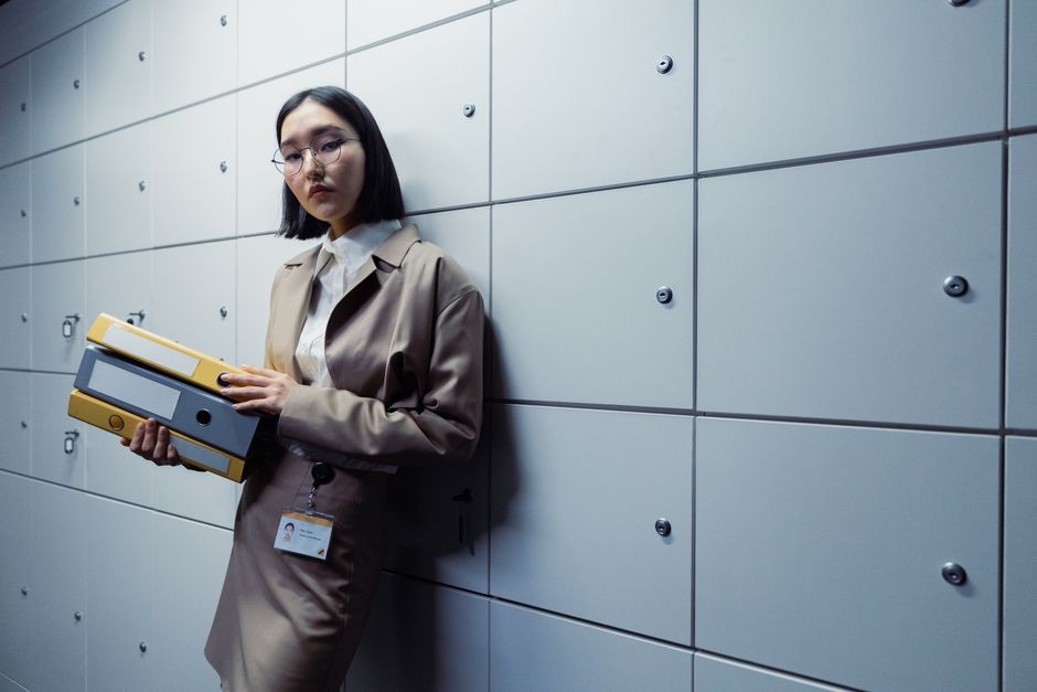 Businesswoman in office attire standing with documents, appearing poised in a modern office setting. Photo by cottonbro studio on Pexels