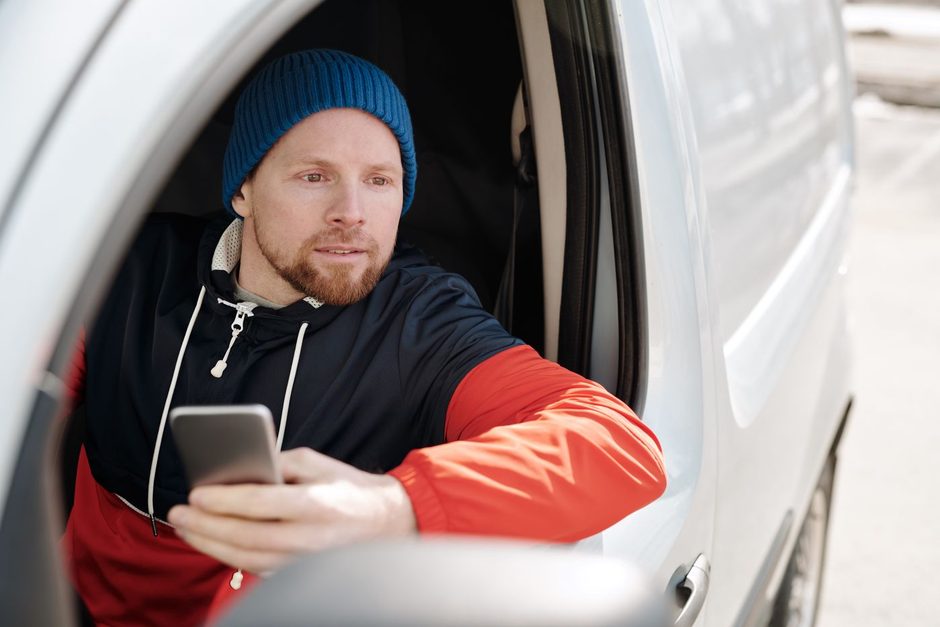 Van driver checking a mobile phone from the cab. Photo by Norma Mortenson on Pexels