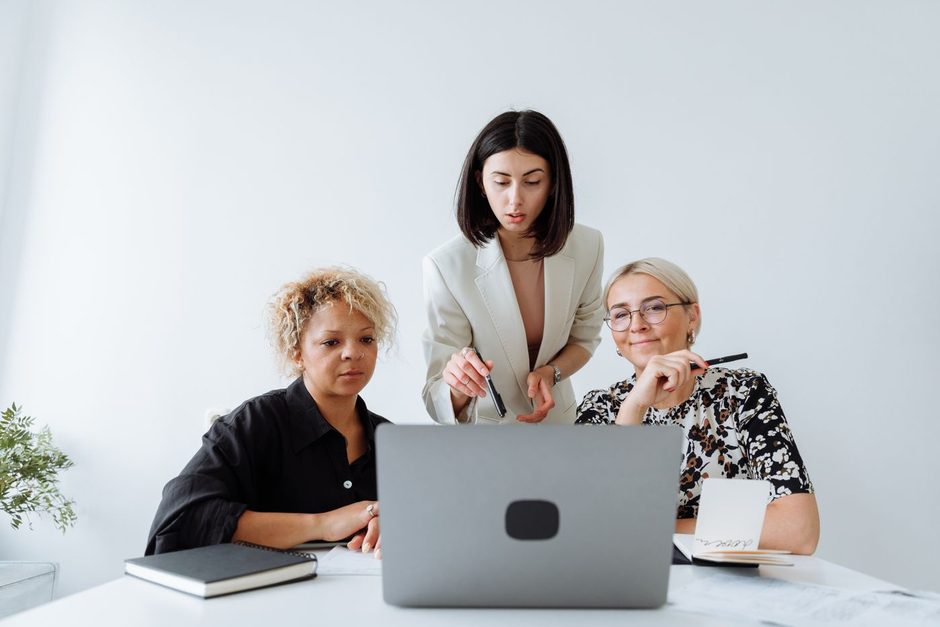 Two women reviewing a laptop together at a desk in a bright office. Photo by Thirdman on Pexels