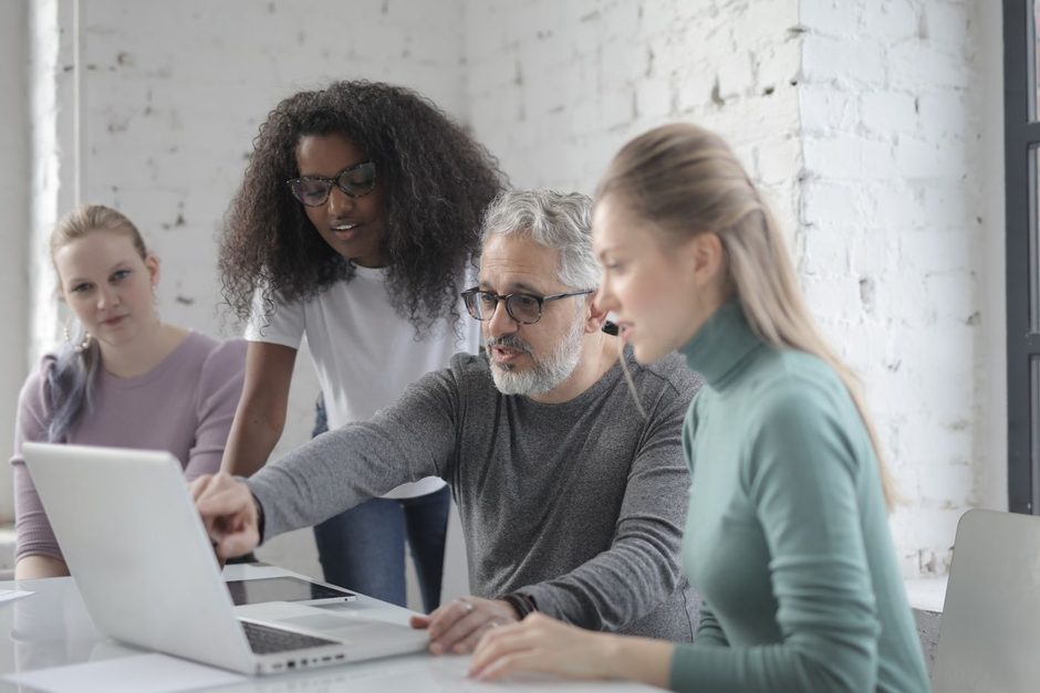 Three colleagues reviewing a laptop screen together in a modern office. Photo by Andrea Piacquadio on Pexels