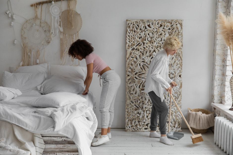 Photo by Monstera Production on Pexels Two women tidying a contemporary bedroom with natural decor elements, showcasing stylish cleaning habits. Photo by Monstera Production on Pexels