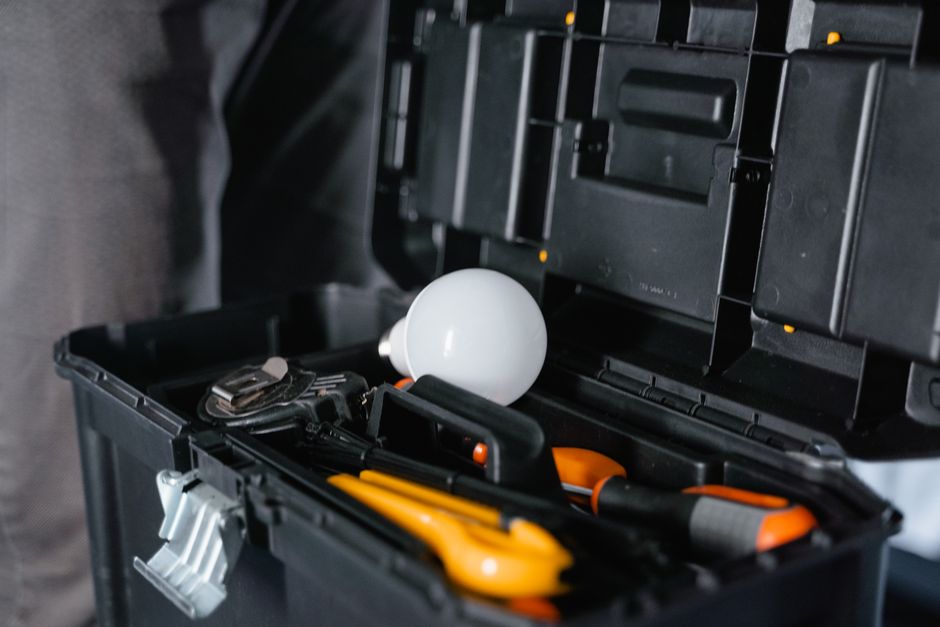 Open toolbox containing various tools and a light bulb. Photo by MART  PRODUCTION on Pexels
