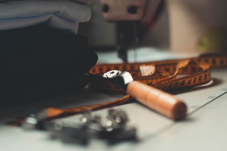 A detailed image of tailoring tools and fabrics on a workbench, perfect for sewing concepts. Photo by Wallace Chuck on Pexels