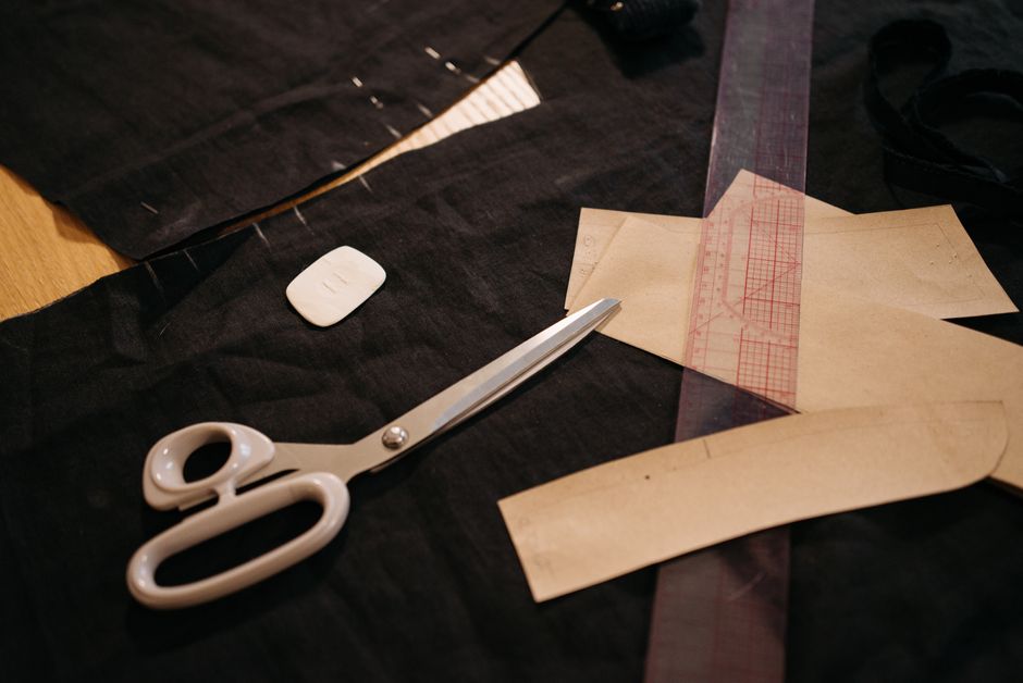 Close-up of tailoring tools including scissors, fabric, and patterns on a workbench. Photo by Pavel Danilyuk on Pexels