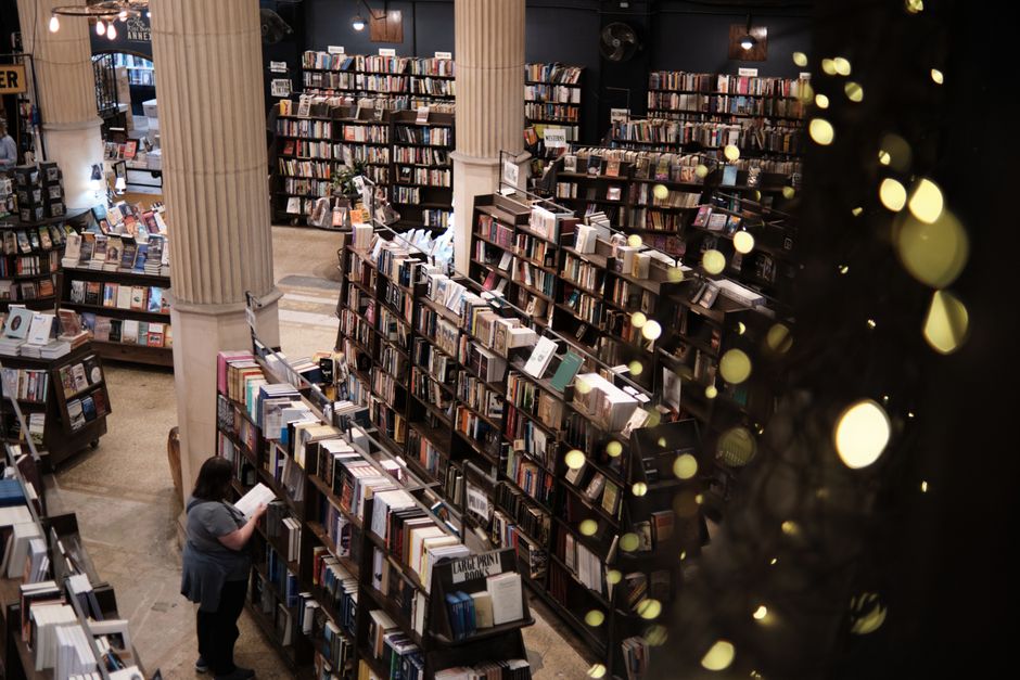 A warm and inviting bookstore interior with stacks of books and a reader. Perfect place for book lovers. Photo by JINGQIN LIN on Pexels