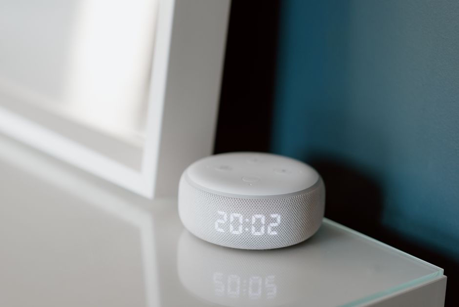 Close-up of a smart speaker with an illuminated 20:02 LED clock display on a desk. Photo by Anete Lusina on Pexels