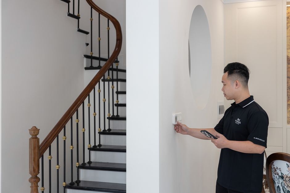 Man adjusting thermostat in stylish home with elegant staircase. Photo by HONG SON on Pexels