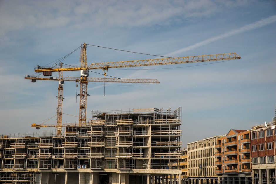 Apartment building under construction with a crane beside it. Photo by Mike van Schoonderwalt on Pexels