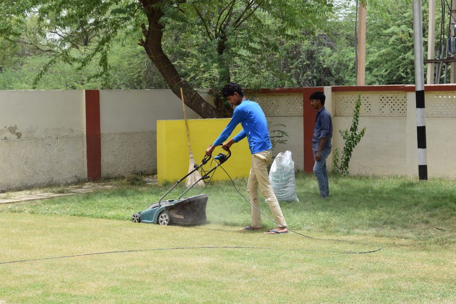 Photo by Rajesh S Balouria on Pexels Young men working together on lawn maintenance with a mower in a sunny garden setting. Photo by Rajesh S Balouria on Pexels