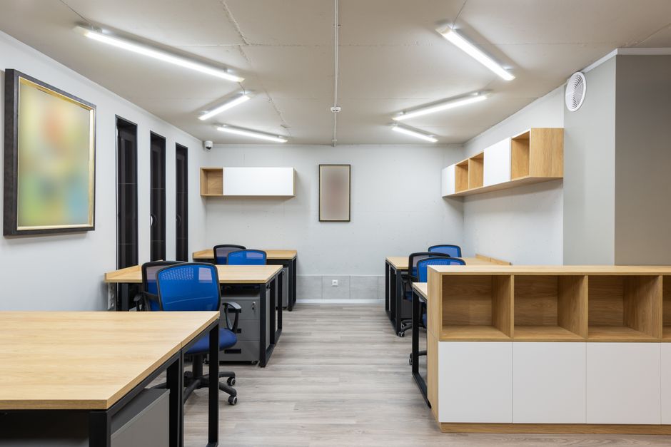 Interior of contemporary workspace with office chairs at tables and wooden shelves under ceiling with geometric lamps. Photo by Max Vakhtbovych on Pexels