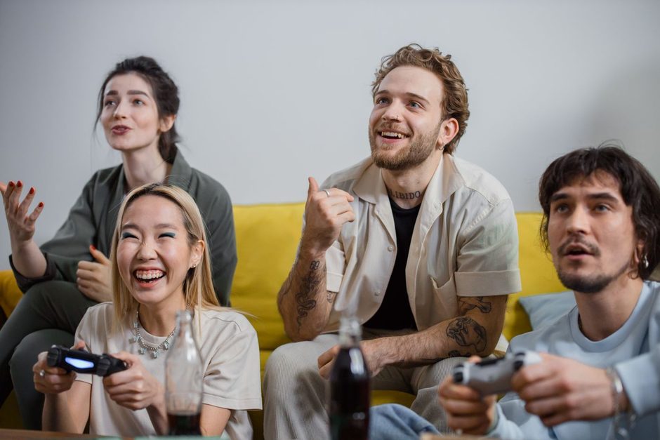Group of friends laughing together on a sofa during a game. Photo by Ron Lach on Pexels