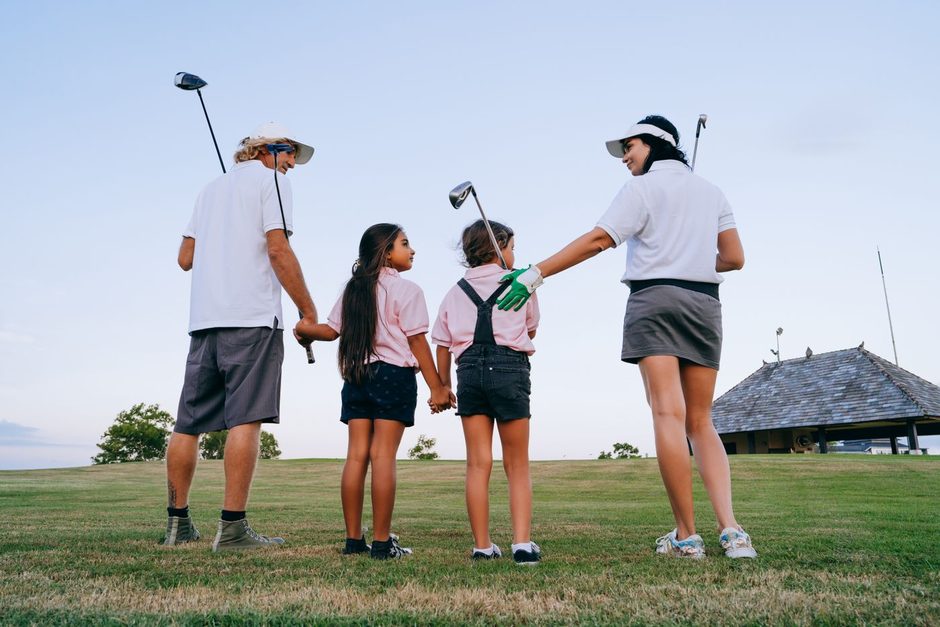 Family walking together on a sunny golf course. Photo by Mikhail Nilov on Pexels