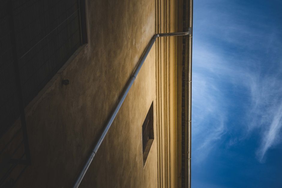 Photo by Francesco Ungaro on Pexels A dramatic view of a yellow building wall with a pipe against a clear blue sky, capturing architectural elegance. Photo by Francesco Ungaro on Pexels