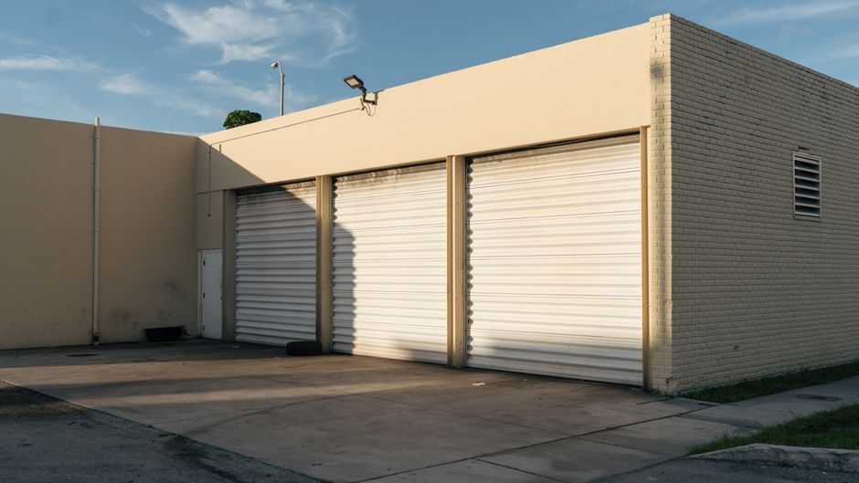 Photo by Sami Abdullah on Pexels Exterior view of a beige industrial building with three closed garage doors under a clear sky. Photo by Sami Abdullah on Pexels